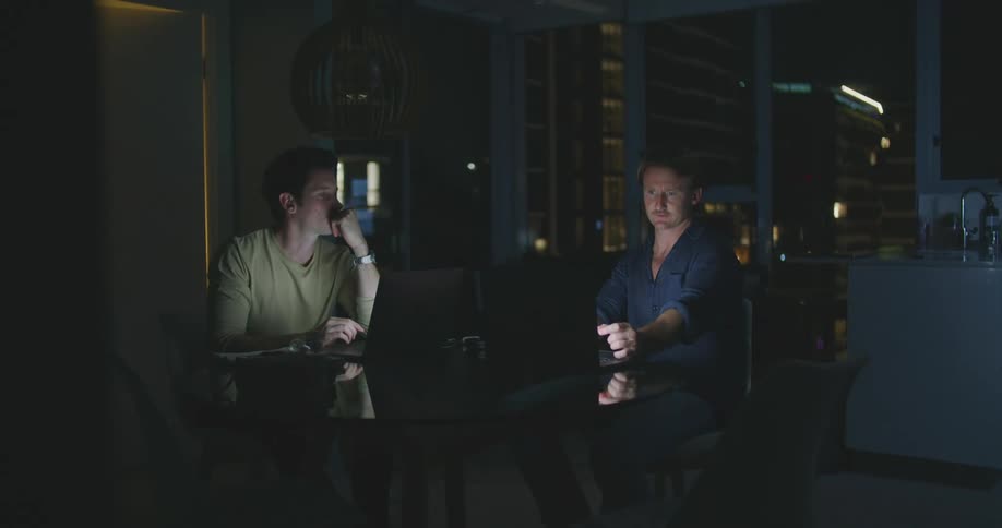 Two men are sitting inside a house at night time