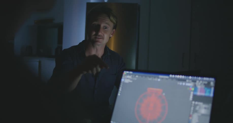 A man talks to another person who has a laptop in front of them and then fist bumps him