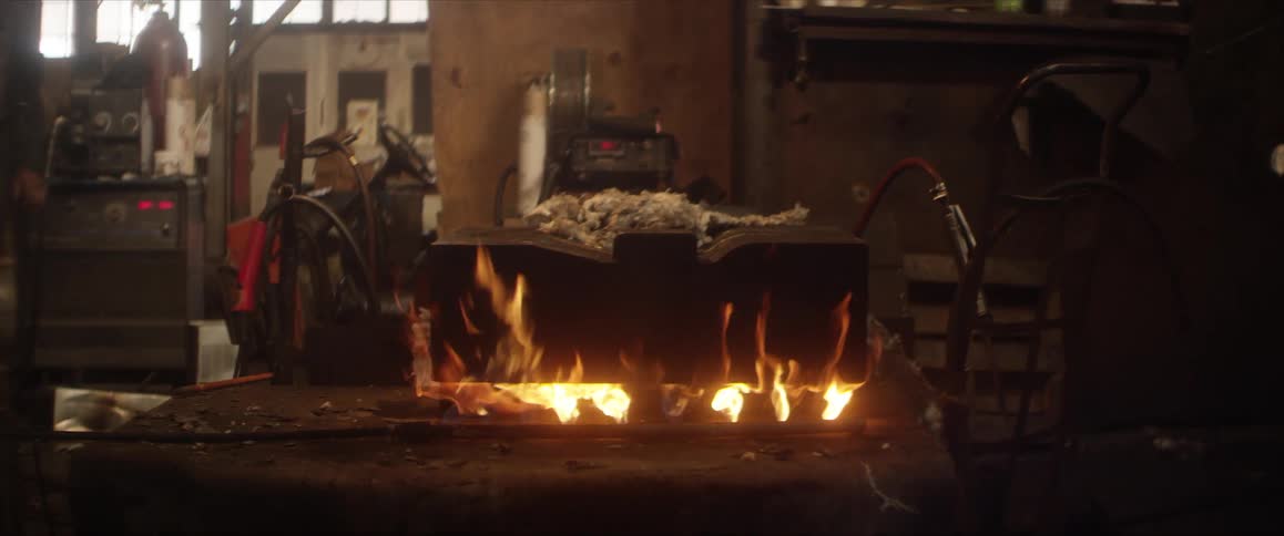A large block of concrete burns over a fire in a factory
