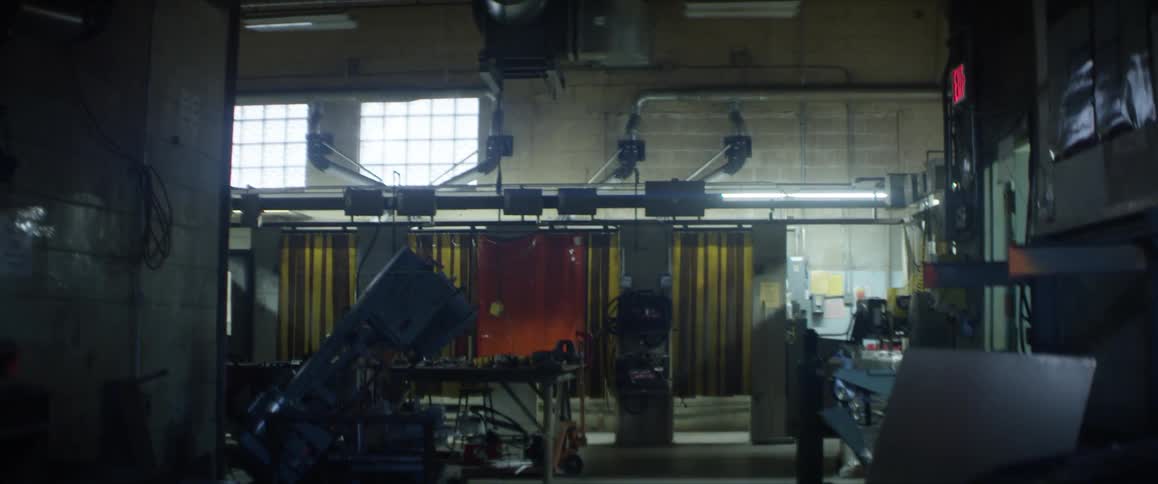 Light from high window brightens workshop with door labeled with lit exit sign