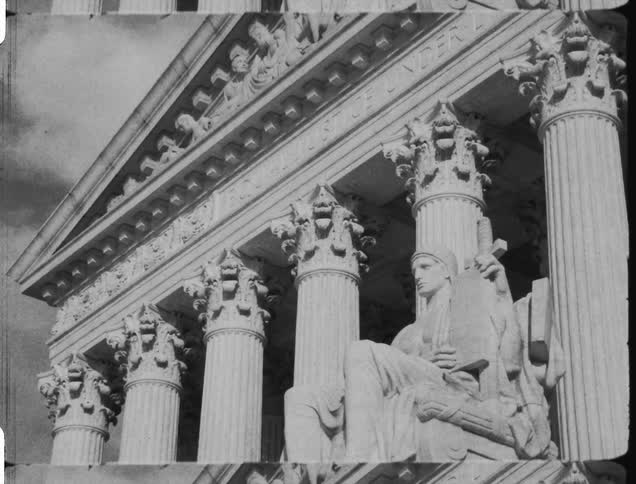 A black and white view of a building and statue