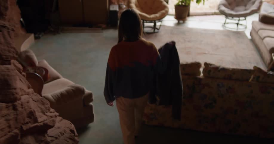 A woman walking in a cave room with a wall and couch in the background