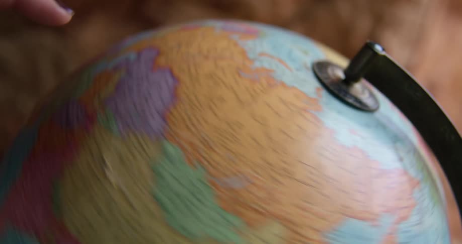 A person spins a globe with their hand