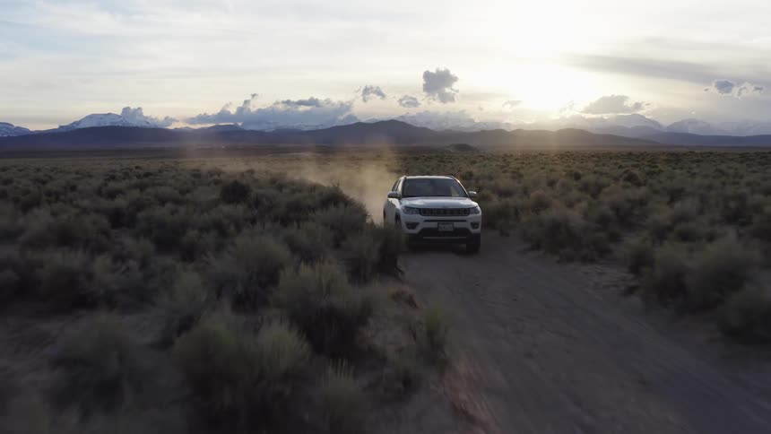 A vehicle drives on a dirt road in a heavily rural area