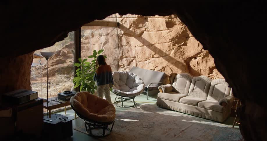 A person walking in a cave room with a wall and couch in the background