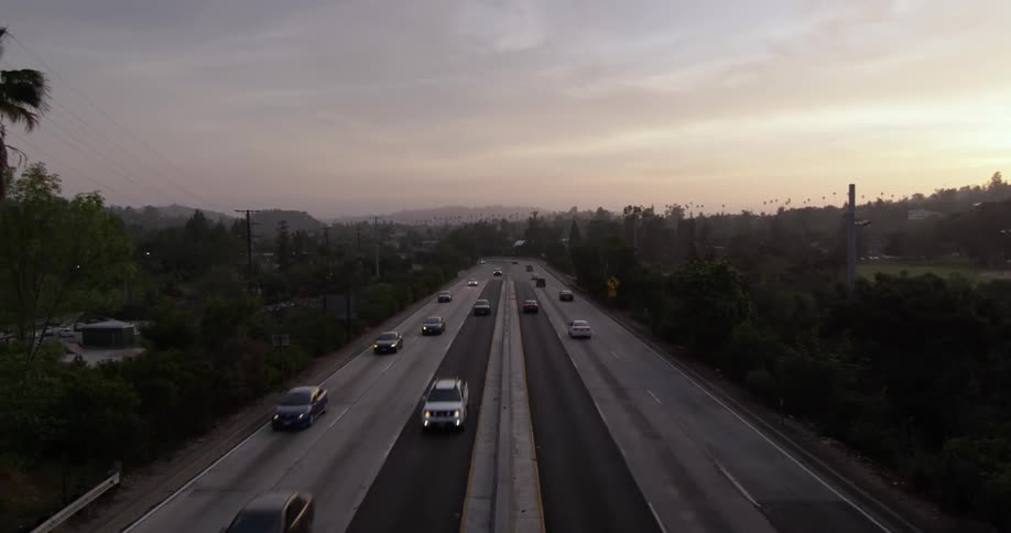 Cars are driving on a highway at sunset