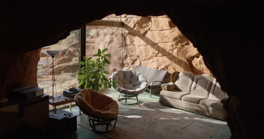An entrance to a living room with a rocky archway with furniture arranged next to a large window