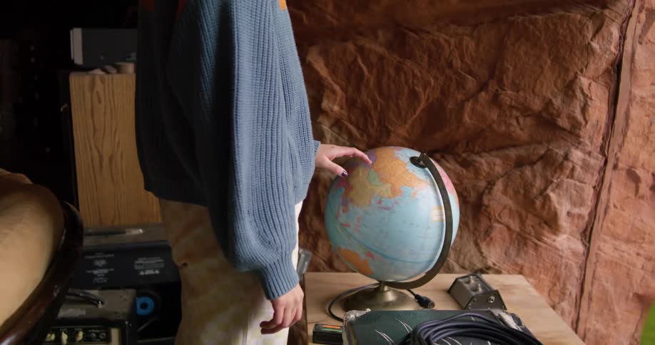 Person stands near natural stone wall spinning globe
