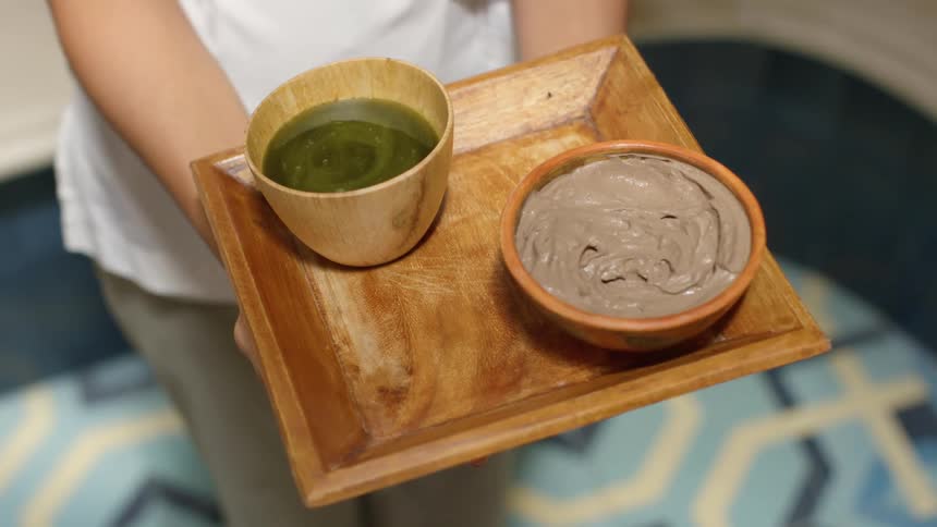 Woman holding a wooden tray containing wooden bowls filled with food