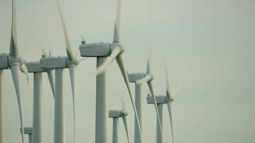 Wind turbines spinning in the wind with the sky and clouds in the background