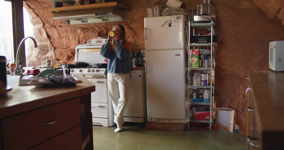 A woman drinking from a mug in a kitchen