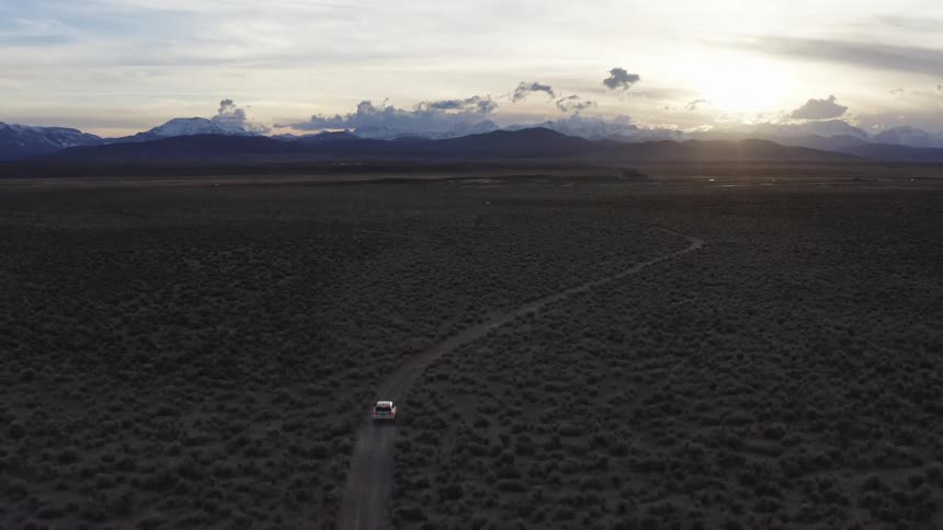 Vehicle driving down a dirt road in the countryside at sunset