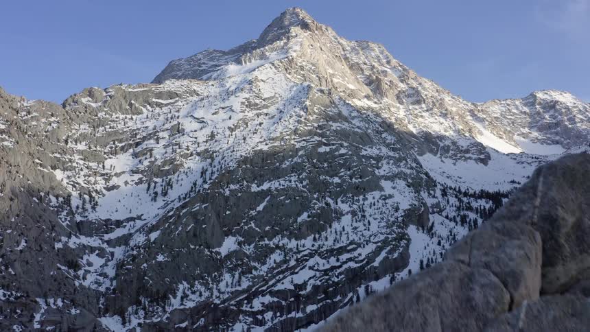 A mountain range with snow and ice with the sky and clouds in the background