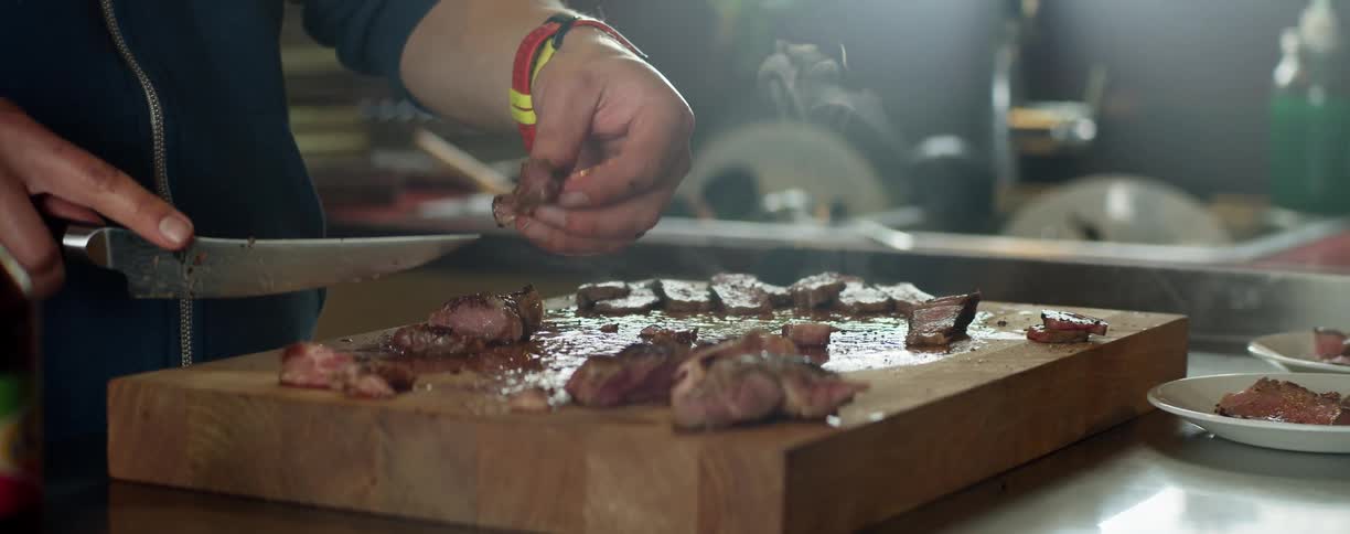 A person is cutting a steak on a cutting board