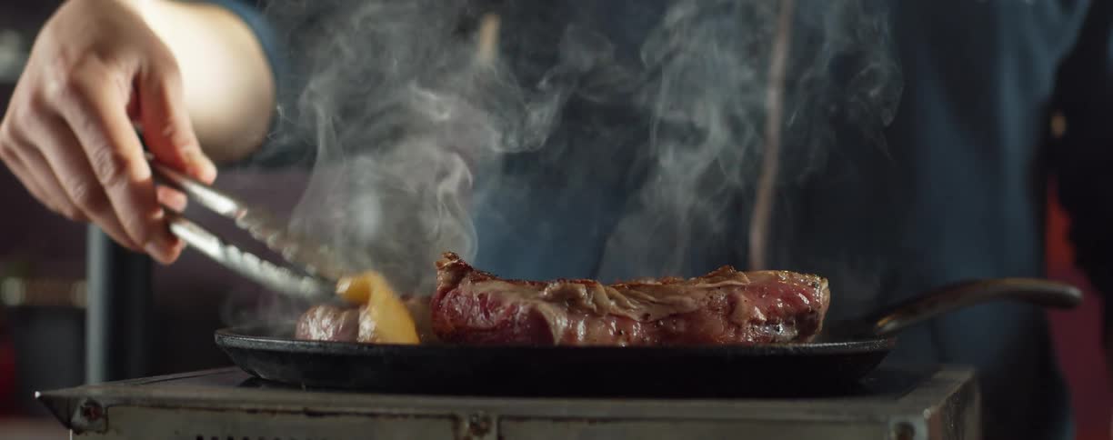 A man cooks steaks at home