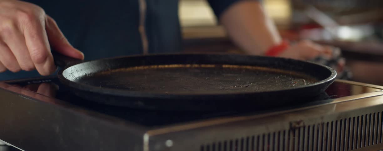 A man places a pan on a burner at home