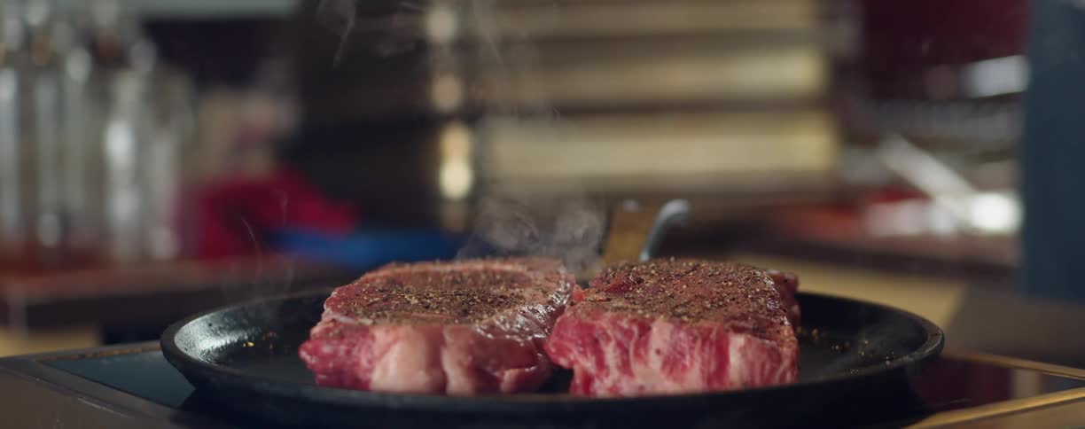 Steaks smoking as they cook on a pan