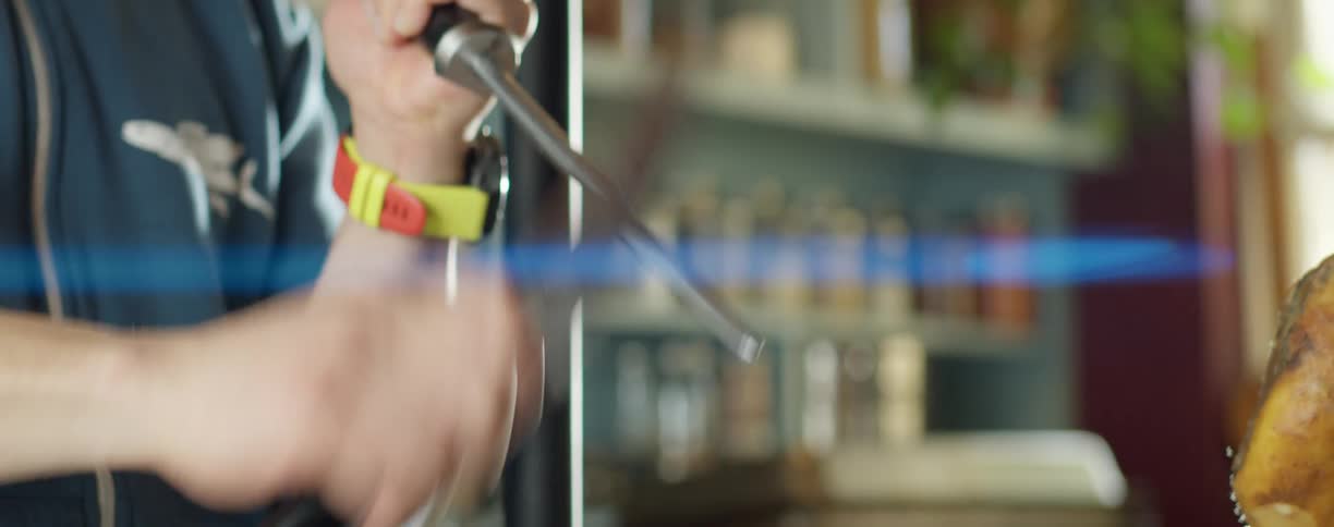 A person in a room sharpening a knife with a wall and window in the background