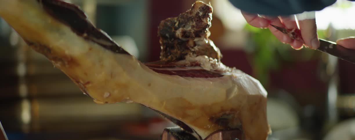A woman cuts meat off a large bone