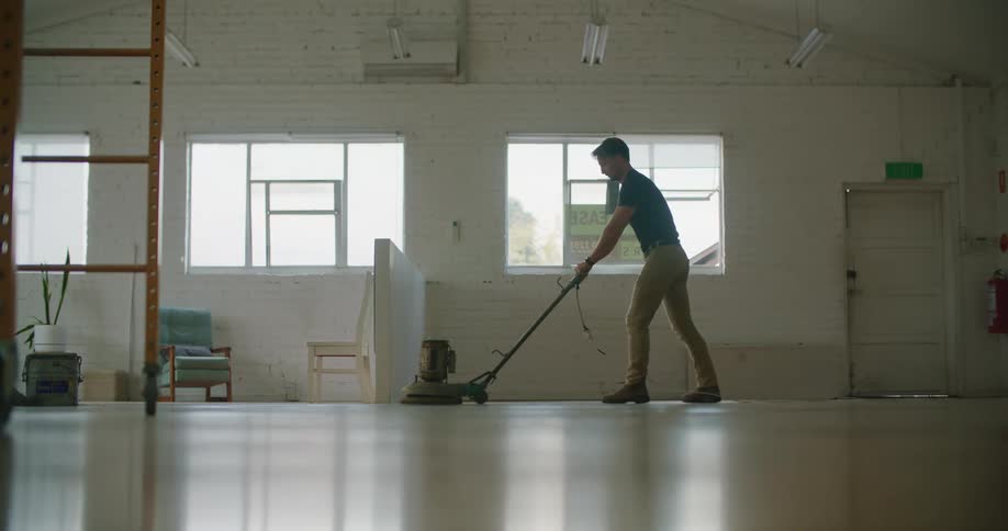 A man polishes the floor of a space that is for lease