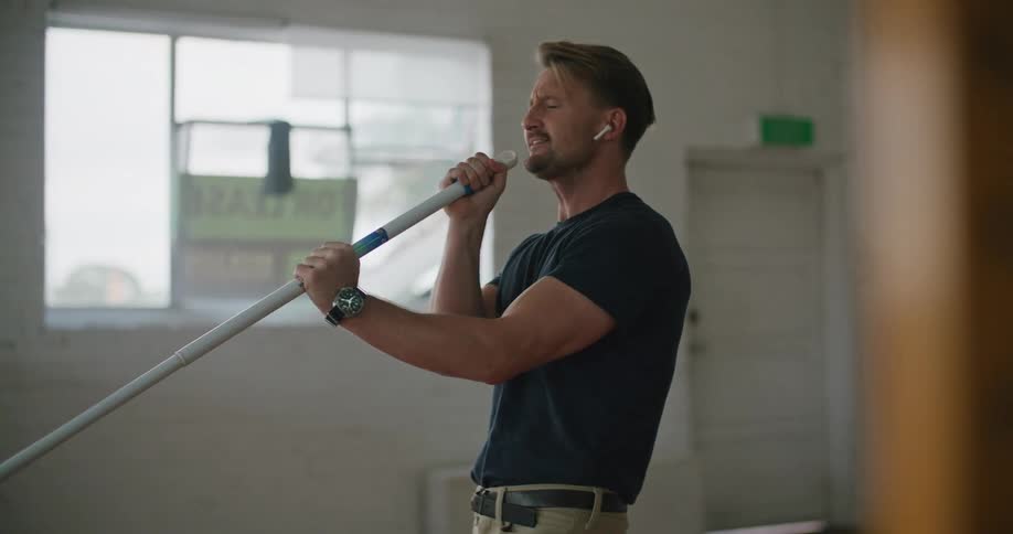 An employ mopping and singing into a mop pole