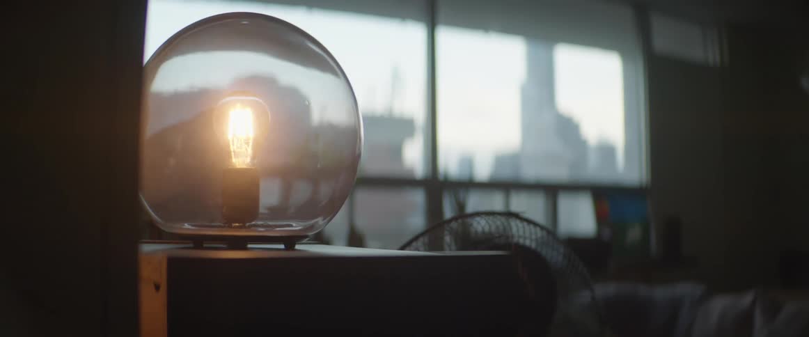 A circle shaped lamp on a desk in a room turned on