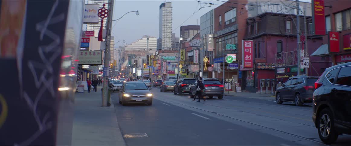 Pedestrians jaywalk in front of vehicle traffic in a busy business district