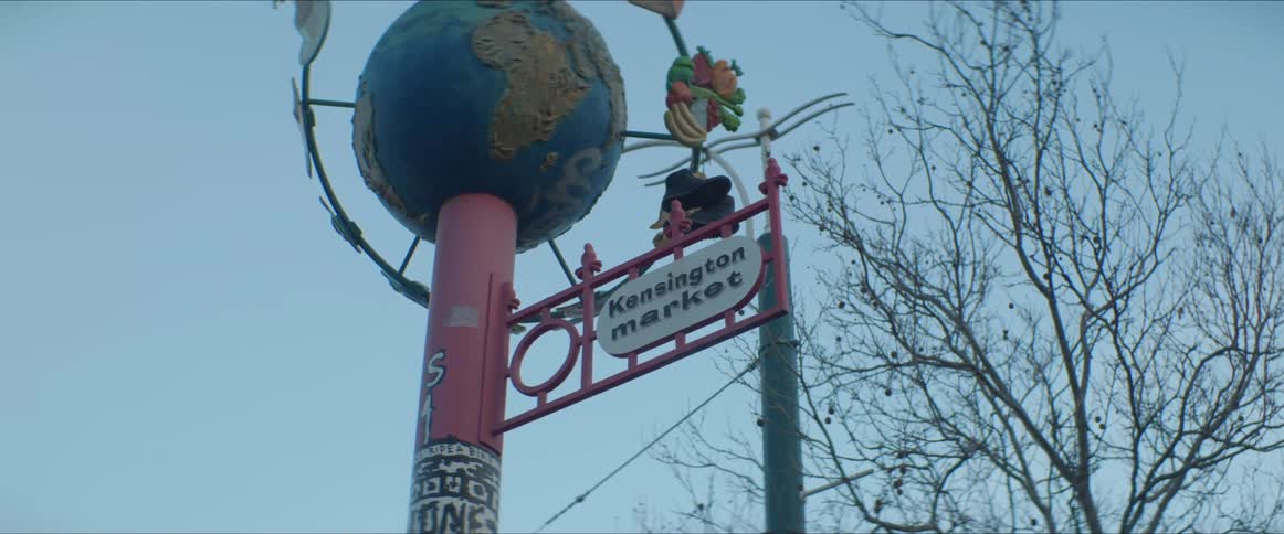 A pole with a sign and a globe with trees the sky and clouds in the background