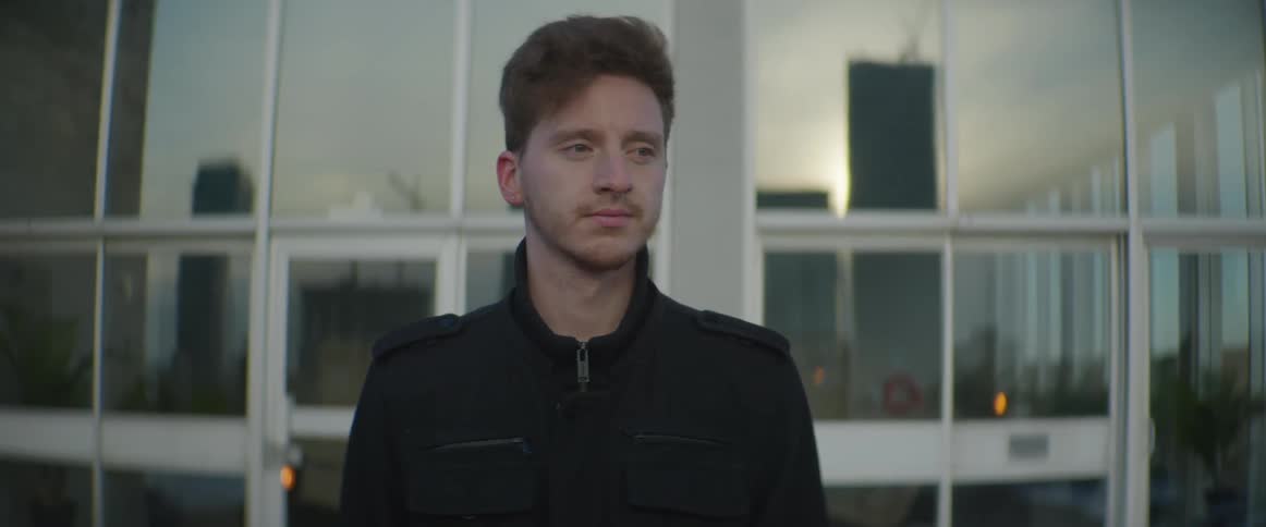 A man with a jacket standing in front of a building