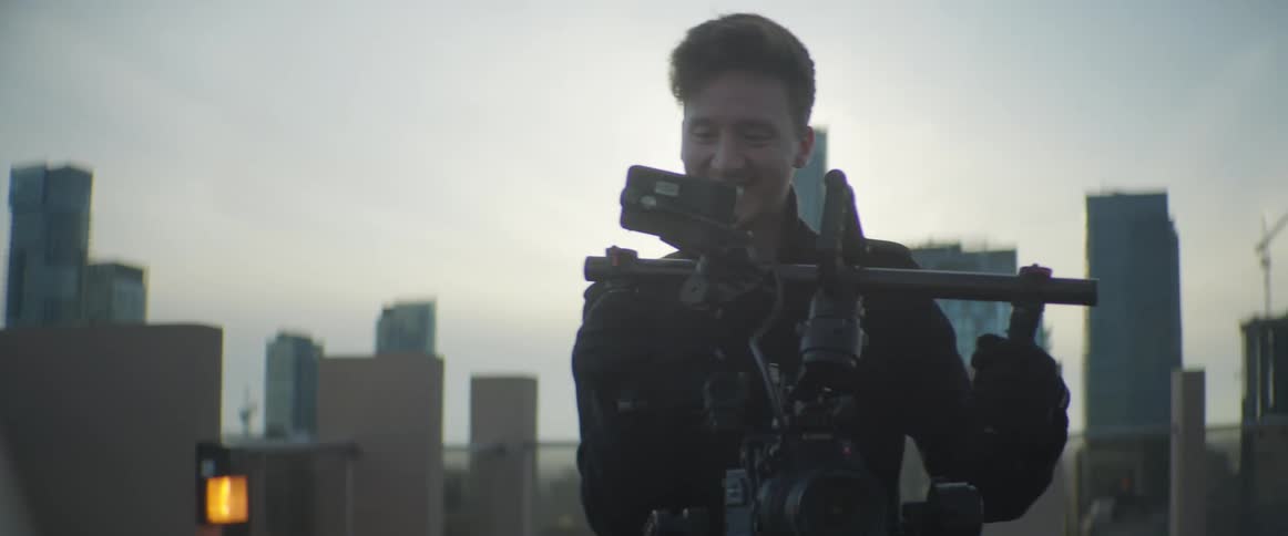 Man using a rig of filming equipment in the city at sunset