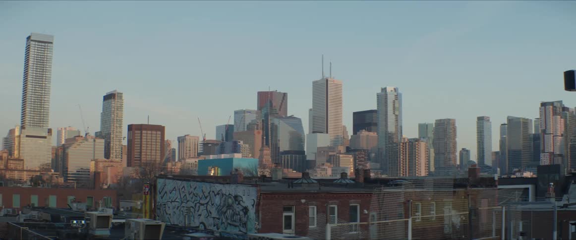 A rooftop with a city skyline the sky and clouds in the background
