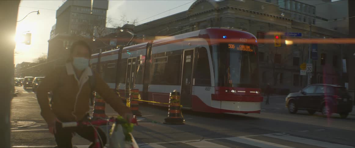 Urban electric train moving on the city street at sunset
