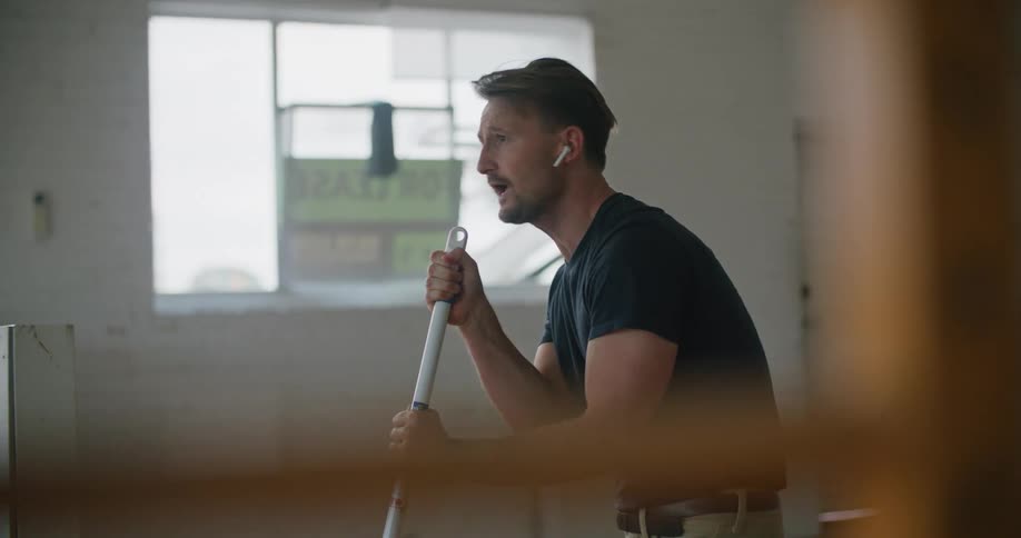 A man sings along to the music in his ear buds while mopping the floor