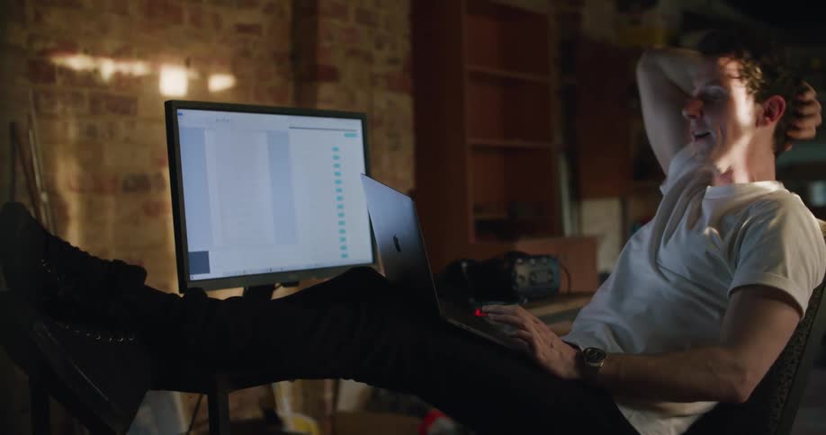 A man that is leaning back in a chair using a computer