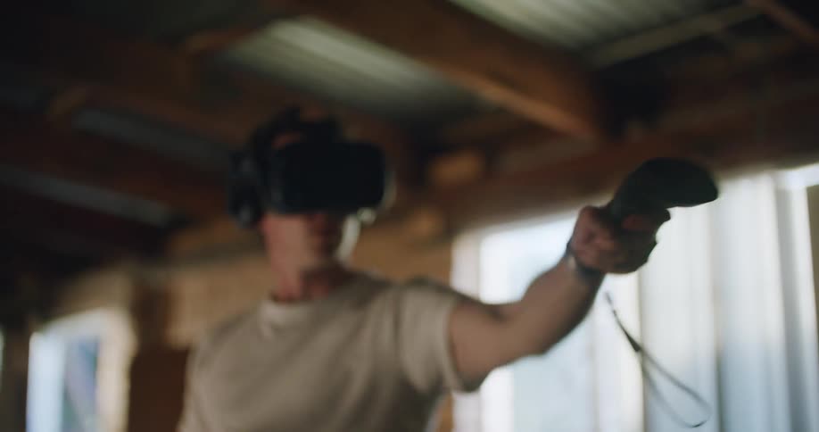 A man wearing a virtual reality headset extends his arm and holds out his controller as if to grab something