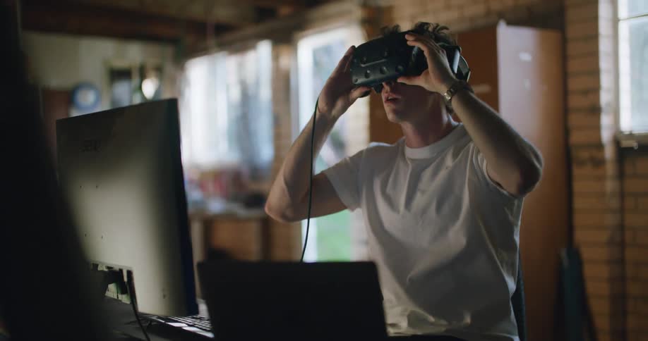 Man testing virtual reality headset in his home office