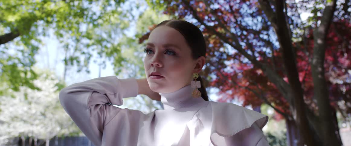 A model posesoutside for a fashion shoot with trees and fence behind her