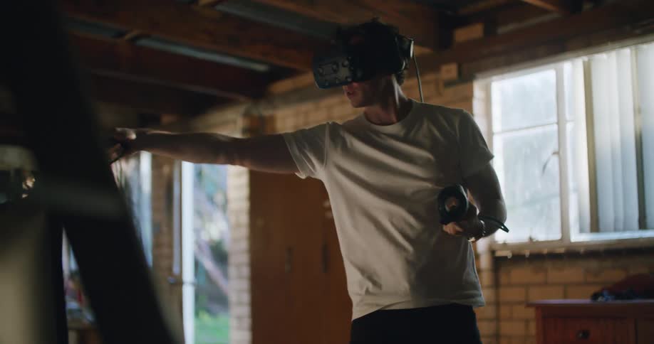 A man points his arms up as he uses a virtual reality headset at home