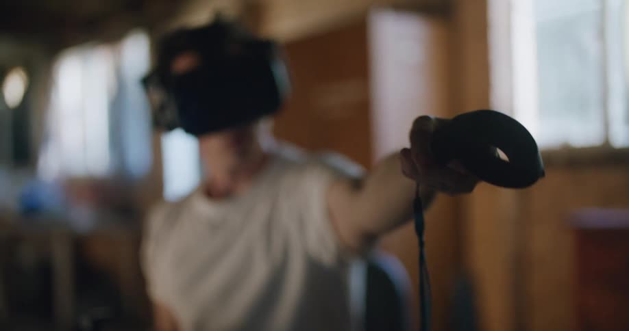 A man sitting on a chair in a room using a black virtual headset