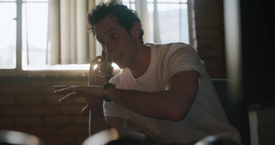Man sitting near window makes call then talks on mobile phone while gesturing