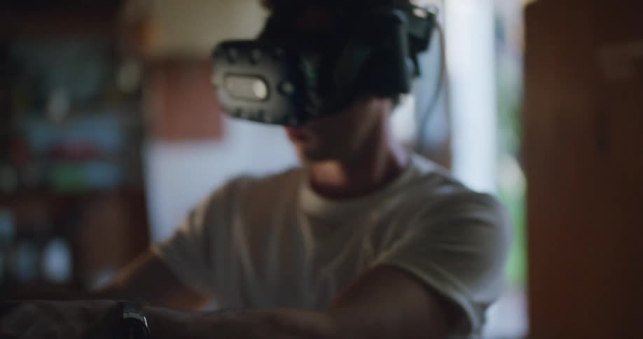 A man with a virtual reality headset in a room with a wall and doorway in the background