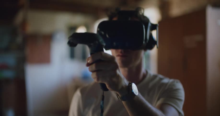 A man with a virtual reality headset in a room with a wall and a doorway in the background