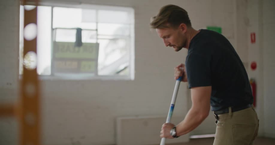 A man takes a break from mopping the wood floor inside an empty business