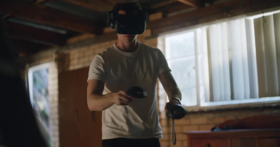 A man with a virtual reality headset in a room with a wall and windows in the background