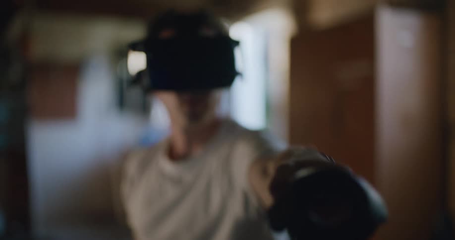 A man wearing virtual reality headset tilts his head and extends his arm holding a controller