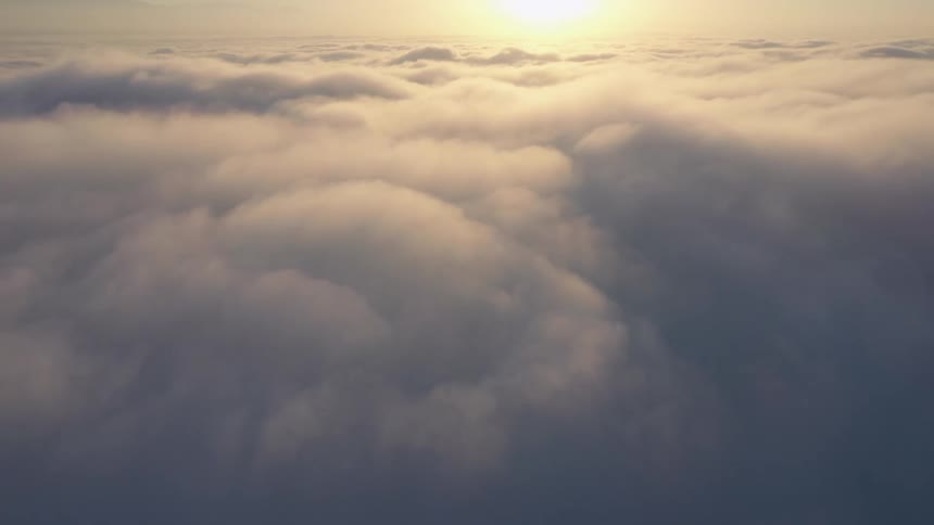 Aerial view over a thick layer of white clouds at sunset