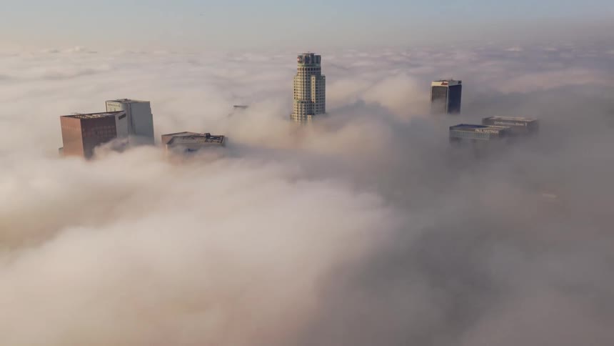 The tops of skyscrapers peak through rolling clouds during the day