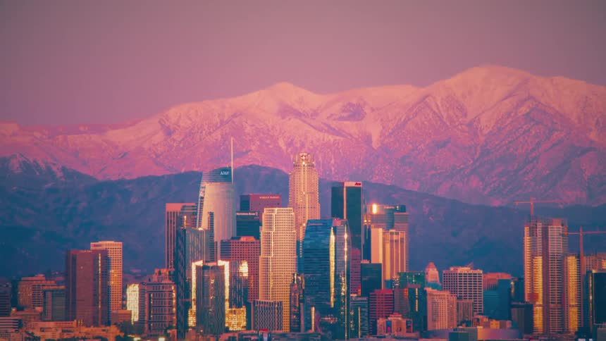 Moon rises over city near mountains before setting again