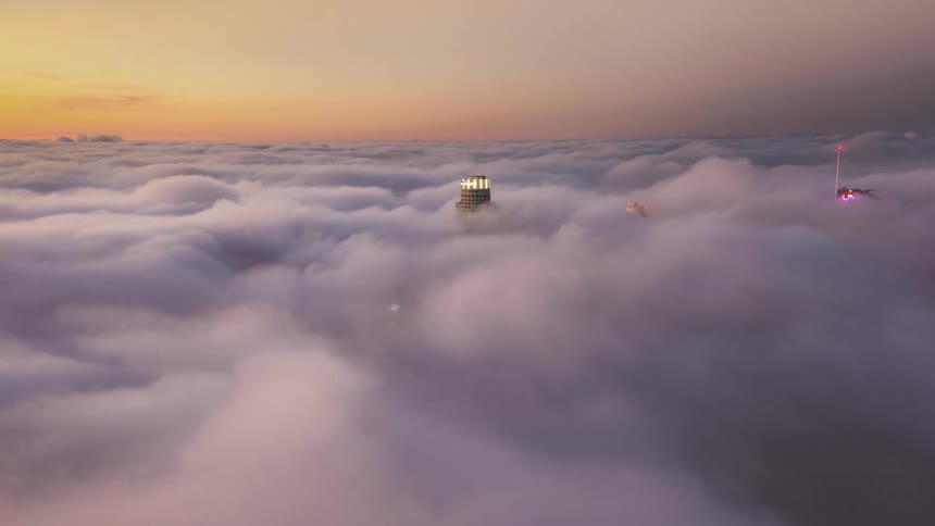Time lapse of clouds rolling over the top of skycrapers at sunset