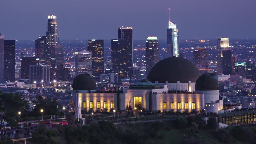 The sun sets as tourists visit griffith observatory with the la skyline glowing behind